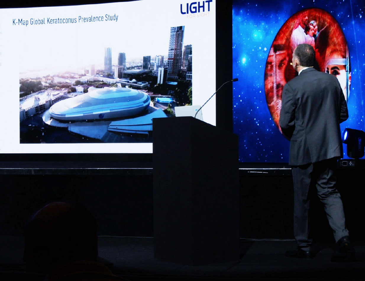 foto del palco di una convention dedicata a Light for Sight, con una proiezione sullo schermo del K-Map Global Prevalence Study e uno speaker al microfono